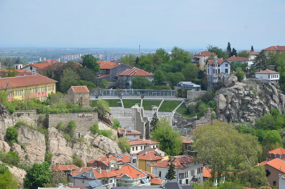Blick über Plovdivs Altstadt mit roten Ziegeldächern und dem antiken Theater zwischen grünen Hügeln.